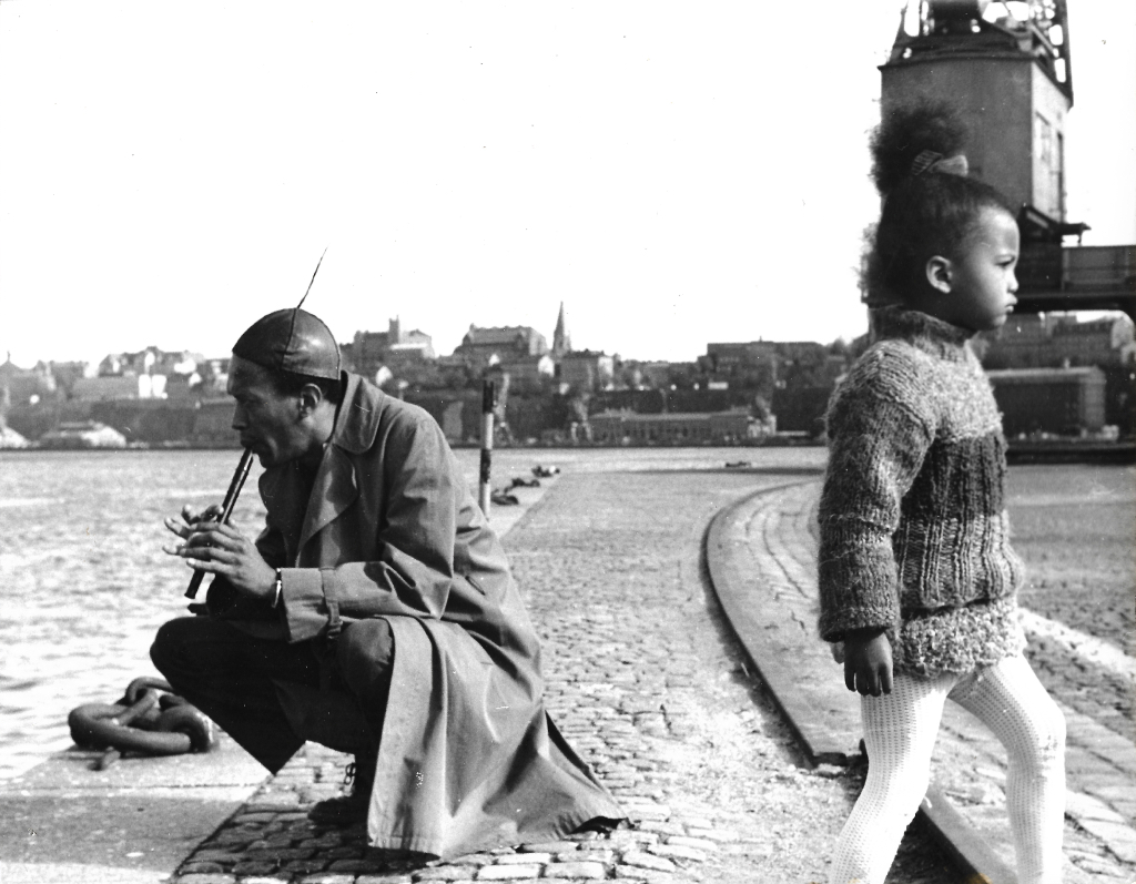 Photo of Don Cherry playing a flute accompanied by his child Neneh Cherry